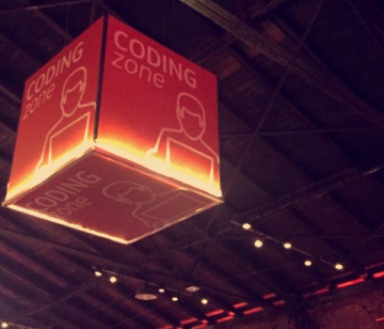 Podwieszany znak „Coding zone” nad parkietem hackathonu